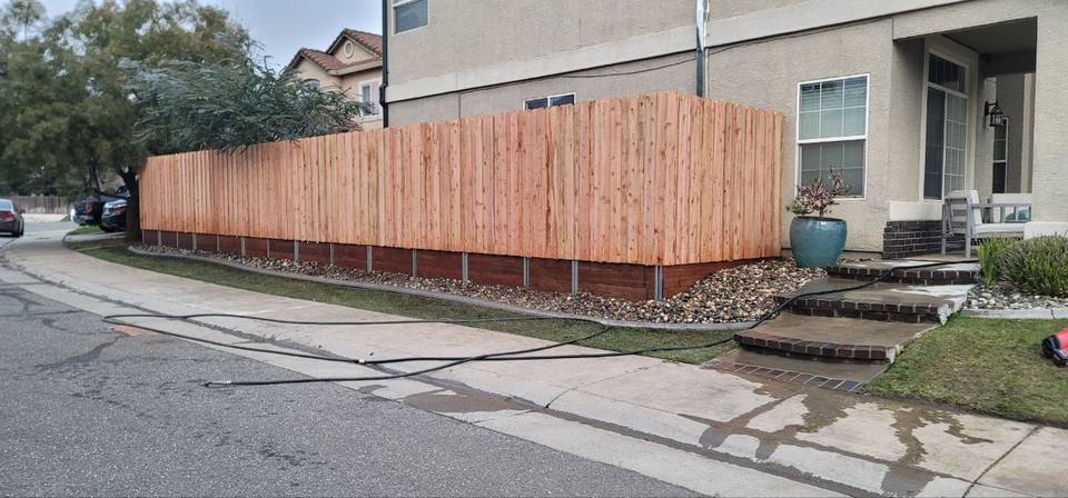 Redwood fence enclosing a backyard patio with string lights