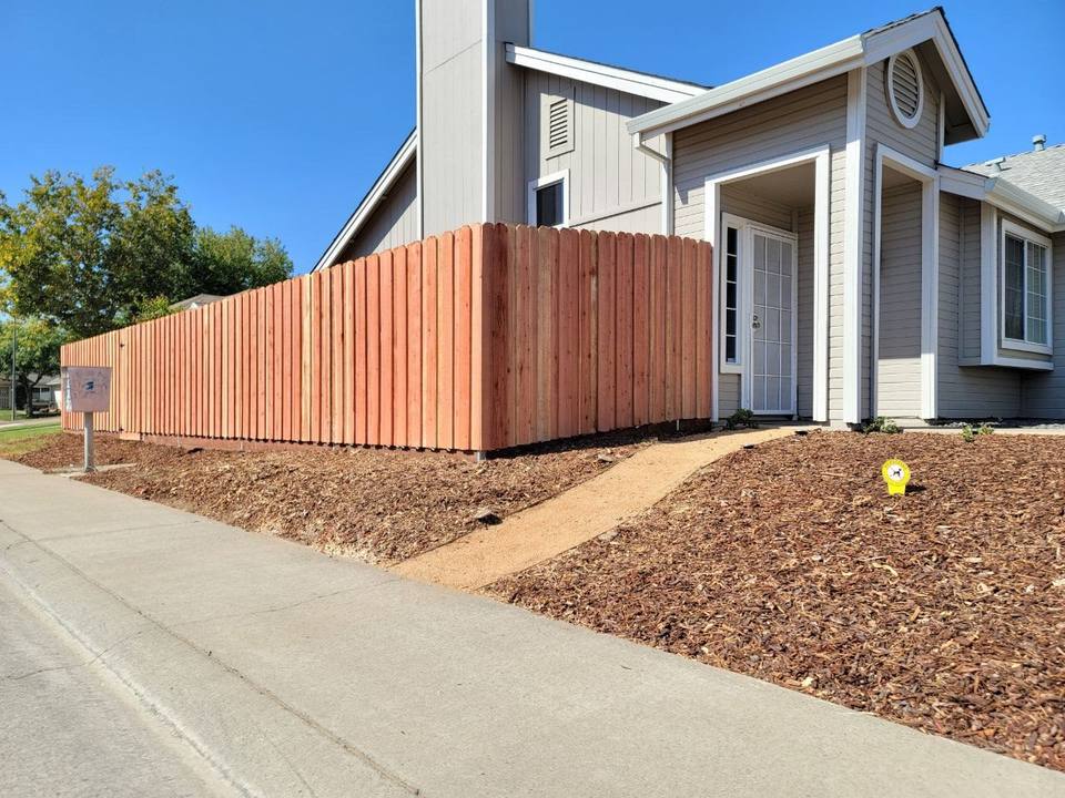 Stained solid wood fence in front of a home